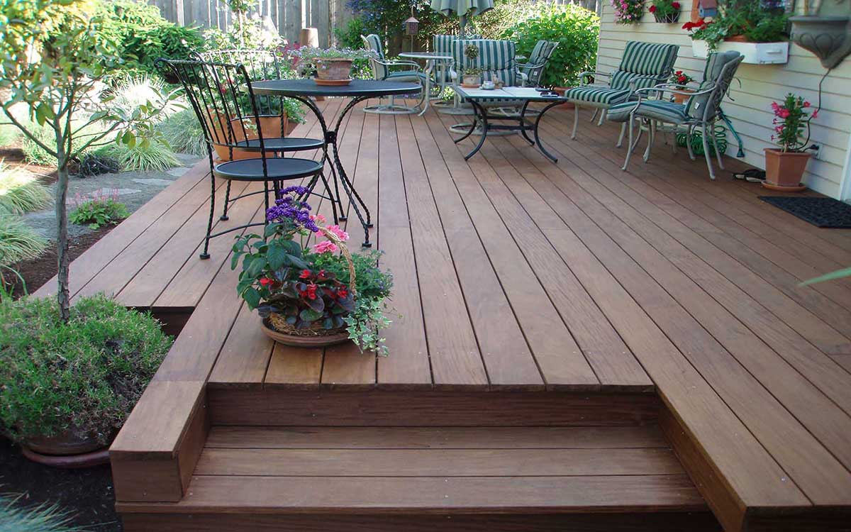 A beautiful dark stained hardwood patio floor with inset stairs, overlooking a detailed garden path.