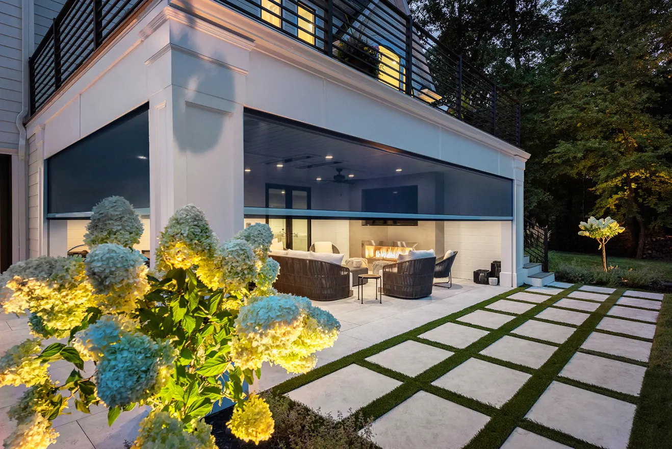 Georgia Luxe Outdoors motorized retractable screens creating an all-season patio enclosure next to a modern stone walkway.