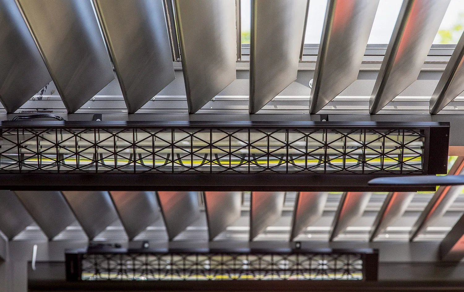Industrial-style electric patio heater mounted directly underneath an open louvered rooftop canopy
