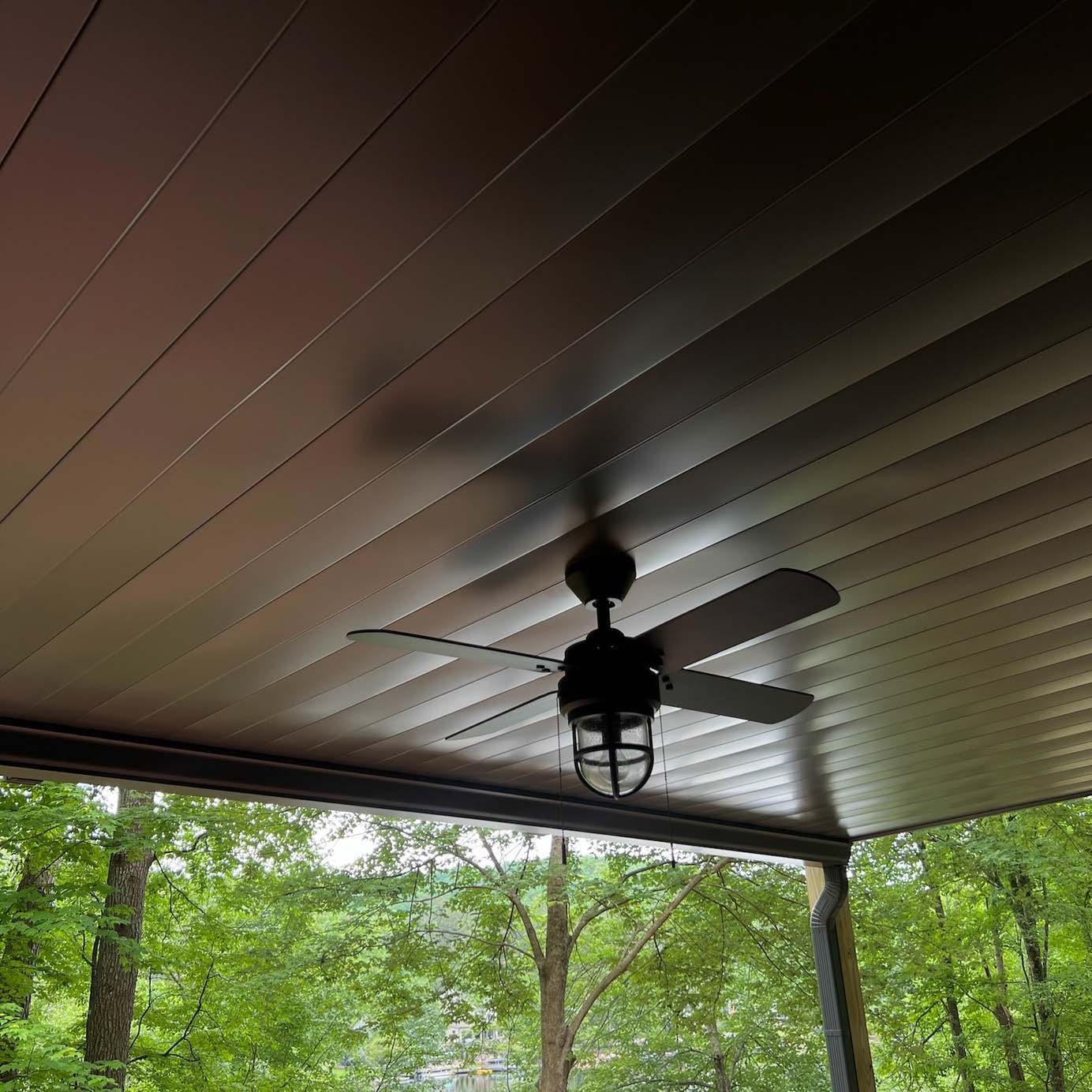Professional hardscape carpentry showing a clean interlocking underdeck panel finish that seamlessly hides the joists and structural wood beams of a deck.