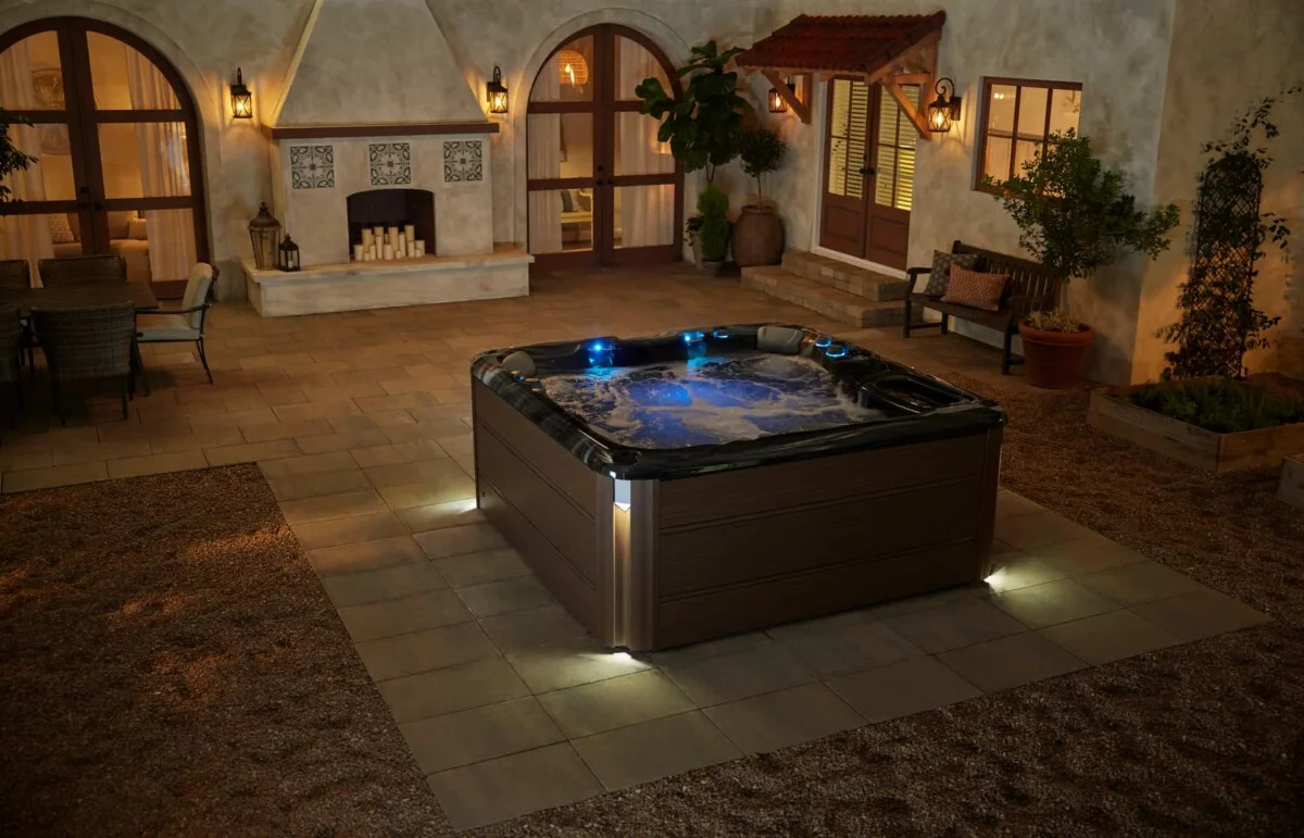 Sundance Spas 880 Cameo home spa model with a dark shell and modern brown hardwood look synthetic cabinetry panels, installed in a private backyard seating area.